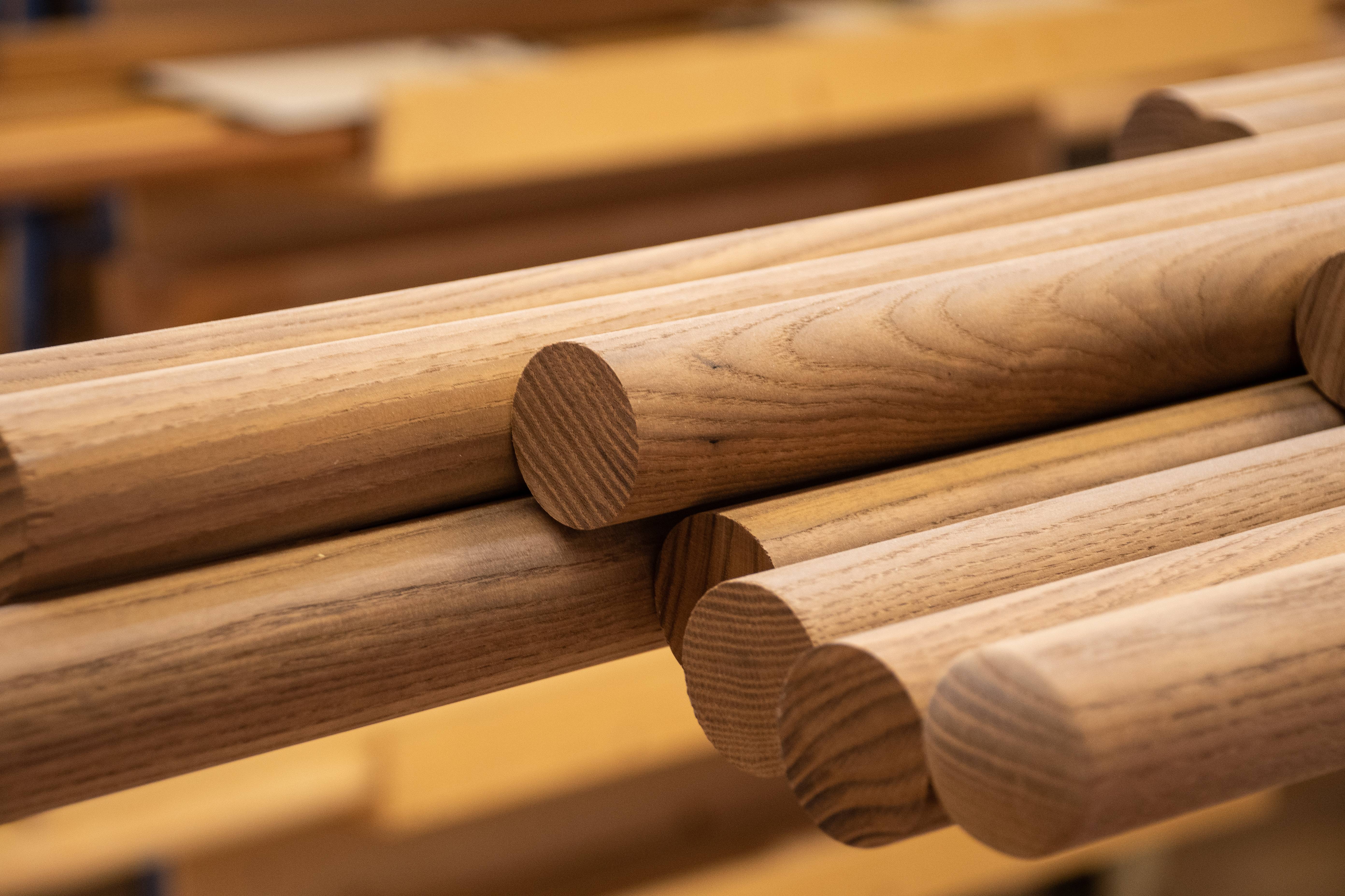 Handlauf Holz rund gestapelt im Werkstattregal, runde Holzstäbe mit sichtbaren Stirnseiten und Maserung, Nahaufnahme