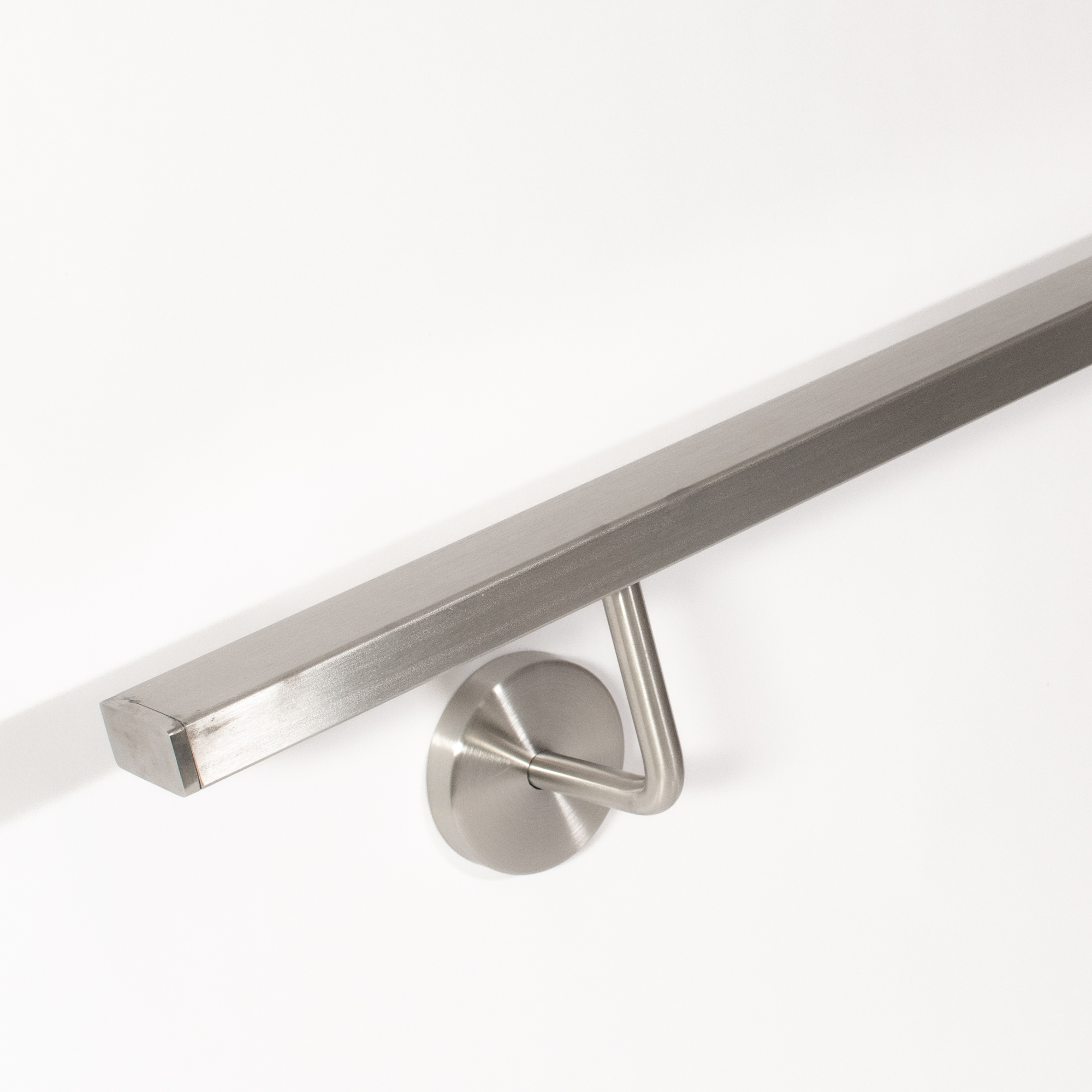 Handlauf Edelstahl rechteckig mit gebogenem Wandhalter Edelstahl, Ansicht von schräg unten mit Handlaufende an weißer Wand
